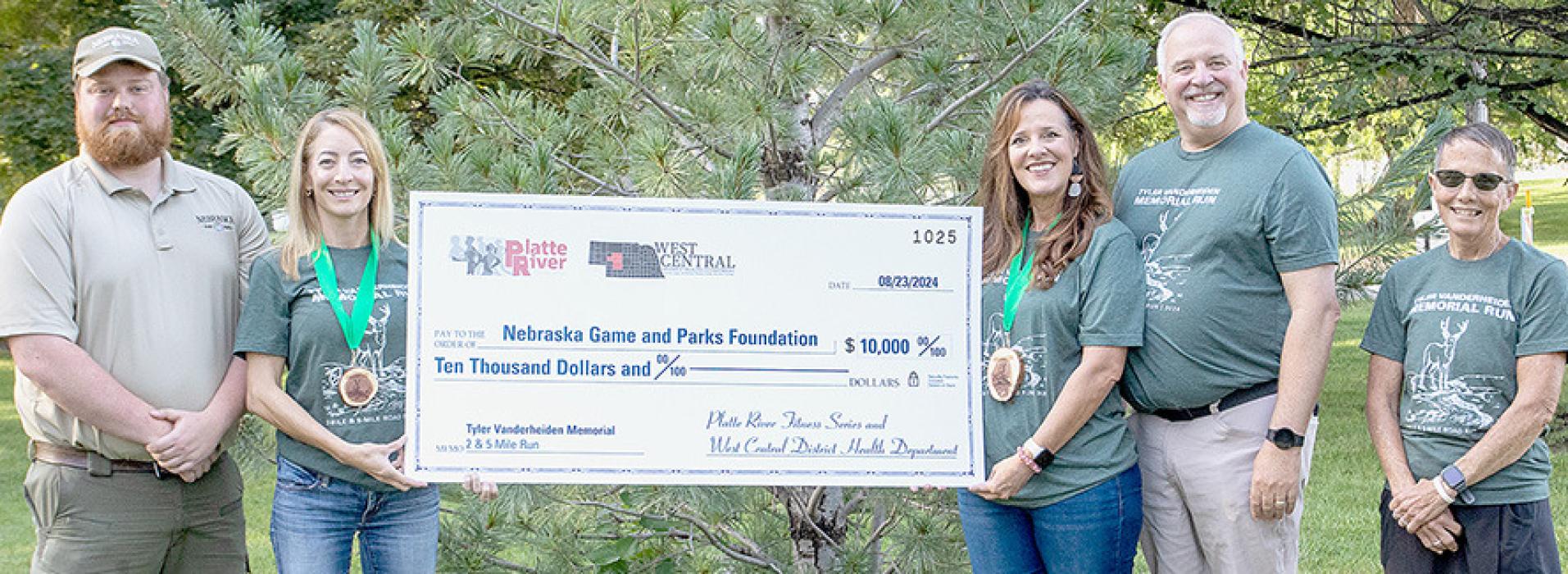 Pictured from left are Smith Falls State Park Superintendent Cody Niewohner, Nebraska Game and Parks Communications Director Christy Firestone, Shannon Vanderheiden and Tim Vanderheiden, Tyler Vanderheiden’s parents; and Trudy Merritt, race organizer of Platte River Fitness Series. (Nebraskaland Magazine/Nebraska Game and Parks Commission)