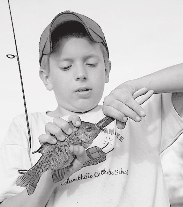 A boy uses a pliers to remove a hook from a bluegill. Several other varieties of hook-removal tools also are available. (Nebraskaland Magazine/NGPC)