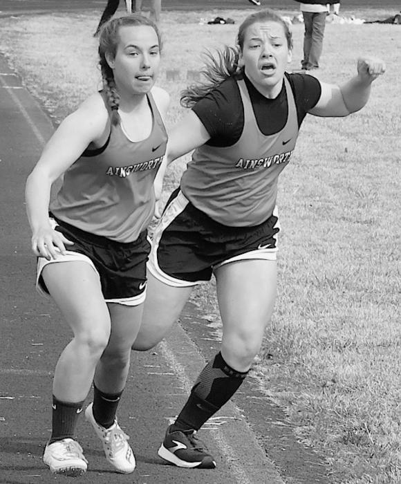 Moriah Beel (right) passes the baton to sister Katrina Beel (left) in the Girls Distance Medley. The team took first place with a time of 14:19.1.