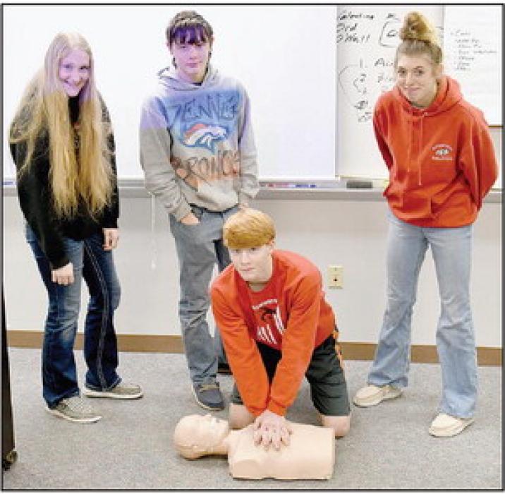 These AHS freshmen, (Standing Left to Right) Addah Booth, Tailor Turpin and Kaitlyn Sease, along with Sam Titus (Kneeling) are learning CPR on a mannequin.