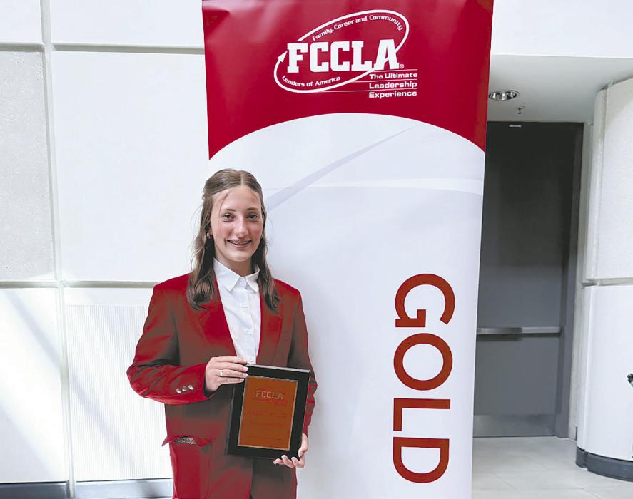 Addilyn Doke stands with her second place plaque. Doke was runner up in the fashion construction division.