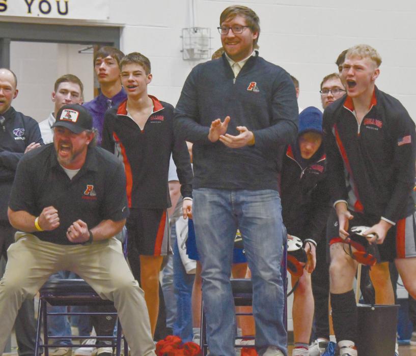 Ainsworth coaches Jake Graff (left) and Nate Fredenburg (right) along with teammates celebrate as Titus wins his match in the heartbreak round to qualify for the state meet.