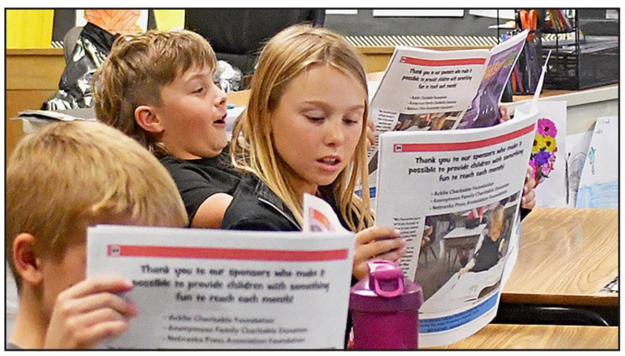 Josh Smith (middle) and Landre Stephen (right) investigate the newest edition of Kid Scoop News. Like a standard newspaper that has sections including Sports, Public Notices and Classified, issues of Kid Scoop News have sections including Health, STEM, Civics, Money Matters, Animals and more.