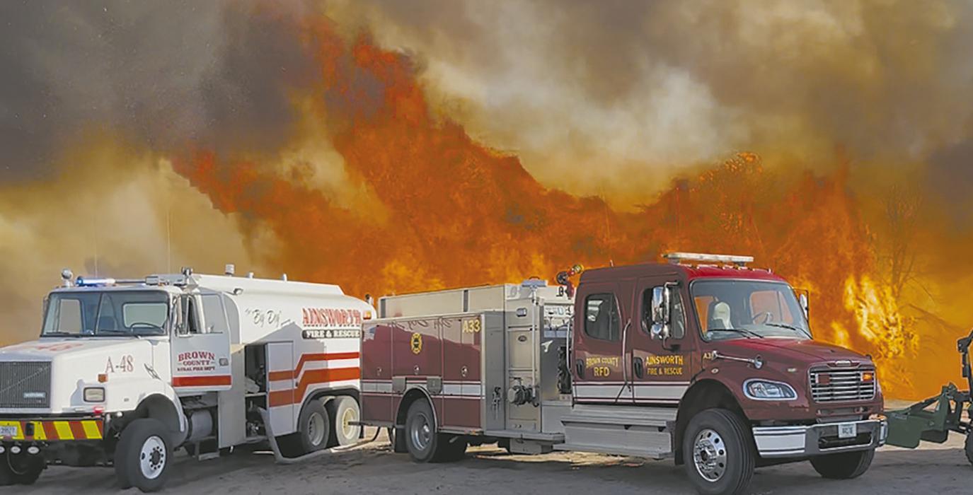 Fire runs rampant behind Ainsworth Fire Department equipment as it protects a home near Norden Avenue. Photo Courtesy of Ann Fiala