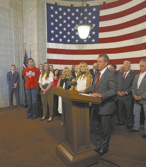 Surrounded by state senators, supporters and female athletes, Governor Jim Pillen signed LB89 into law.